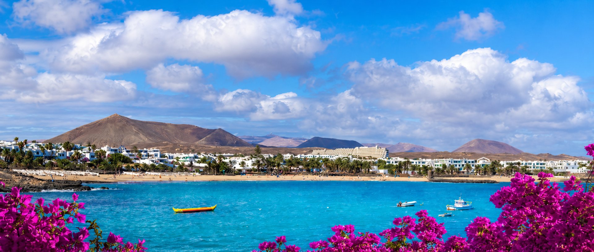 Costa Teguise seafront with golden beach, white houses and volcanic mountains