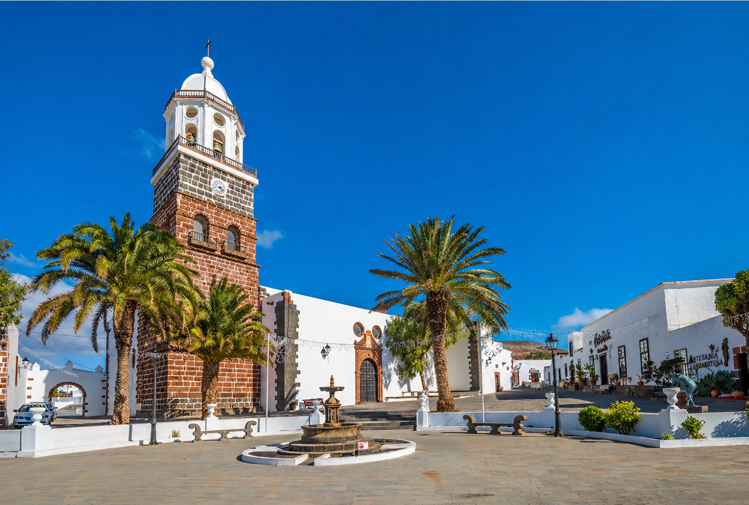 Teguise old town in Lanzarote with whitewashed houses, palm trees and the historic church bell tower under blue sky